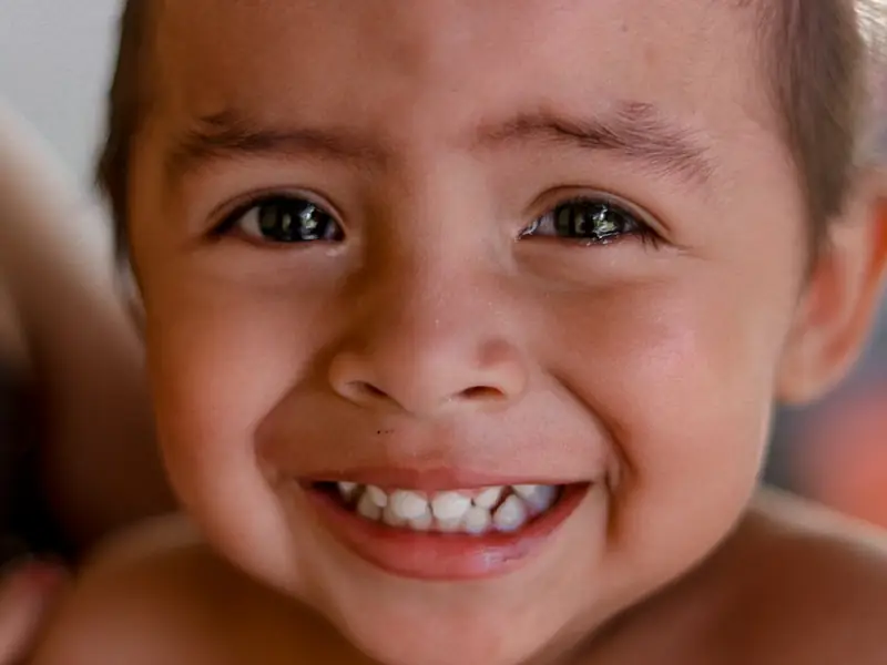 A smiling young child showing his front teeth